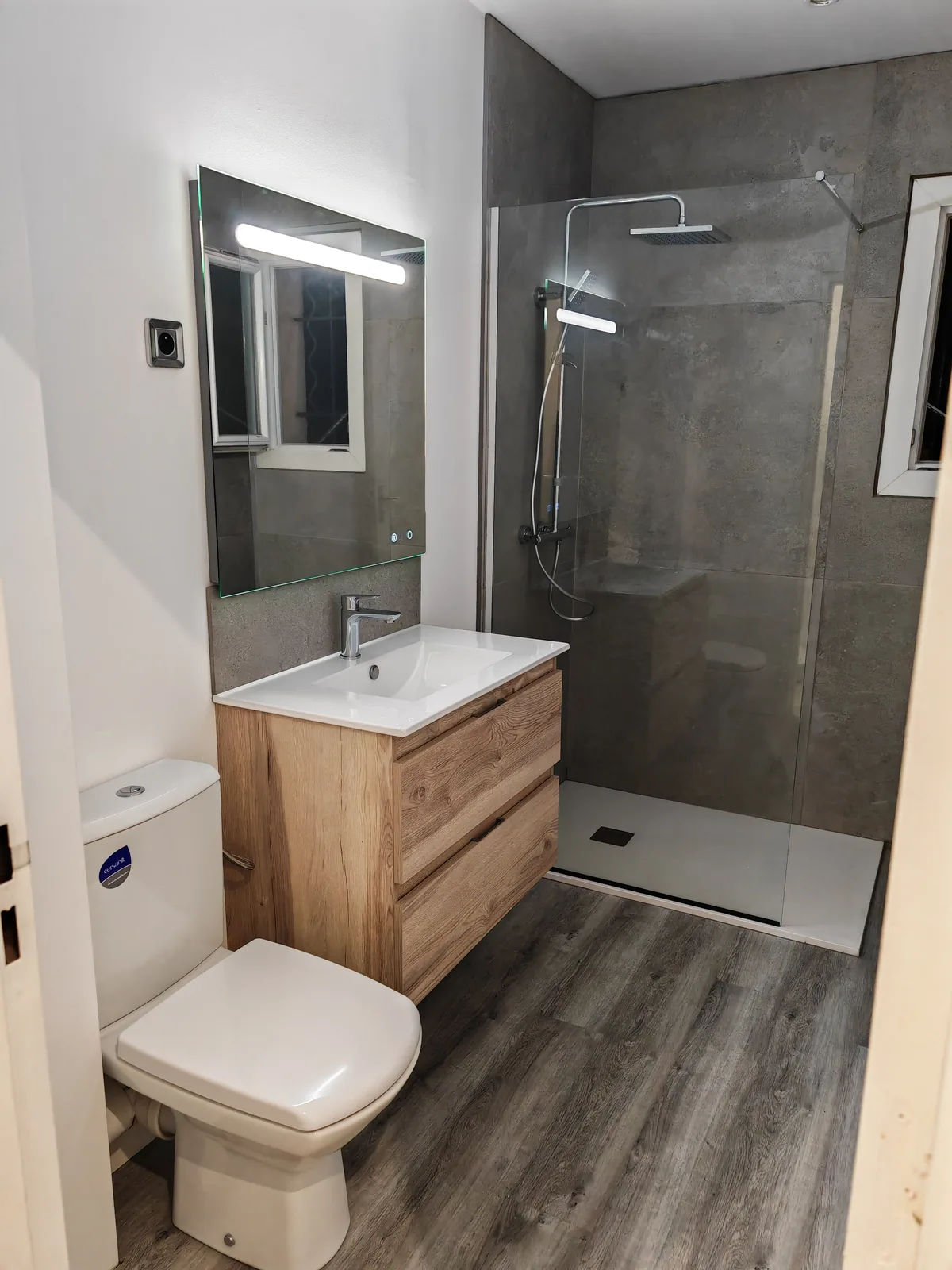 Salle de bain rénovée avec douche, meuble vasque et miroir éclairé